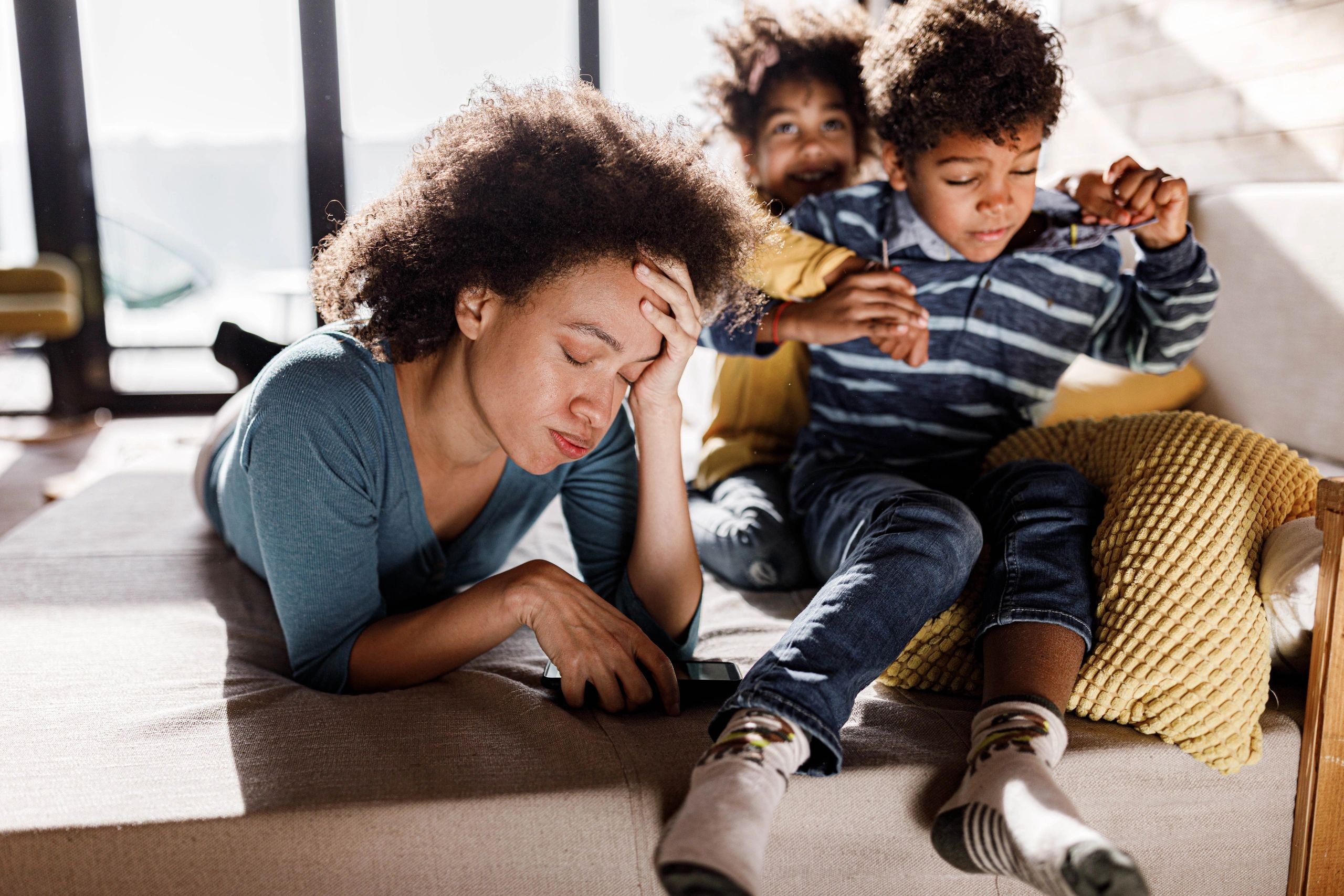 Mom looking overwhelmed while kids play around her at home
