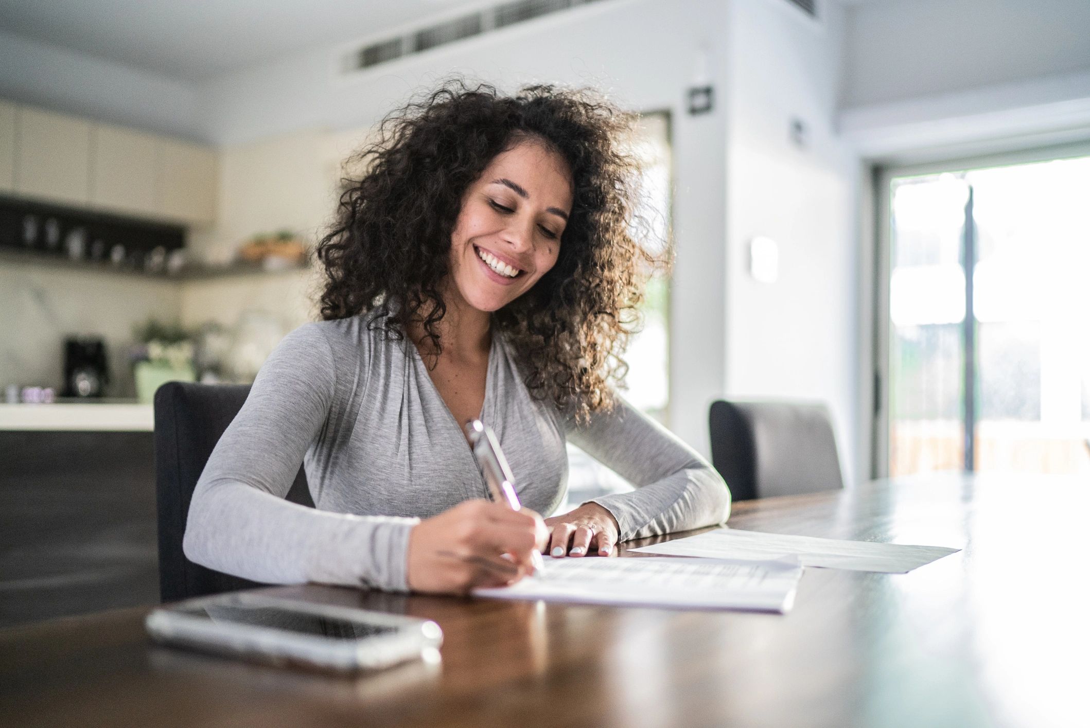 Woman writing in a journal at a kitchen table