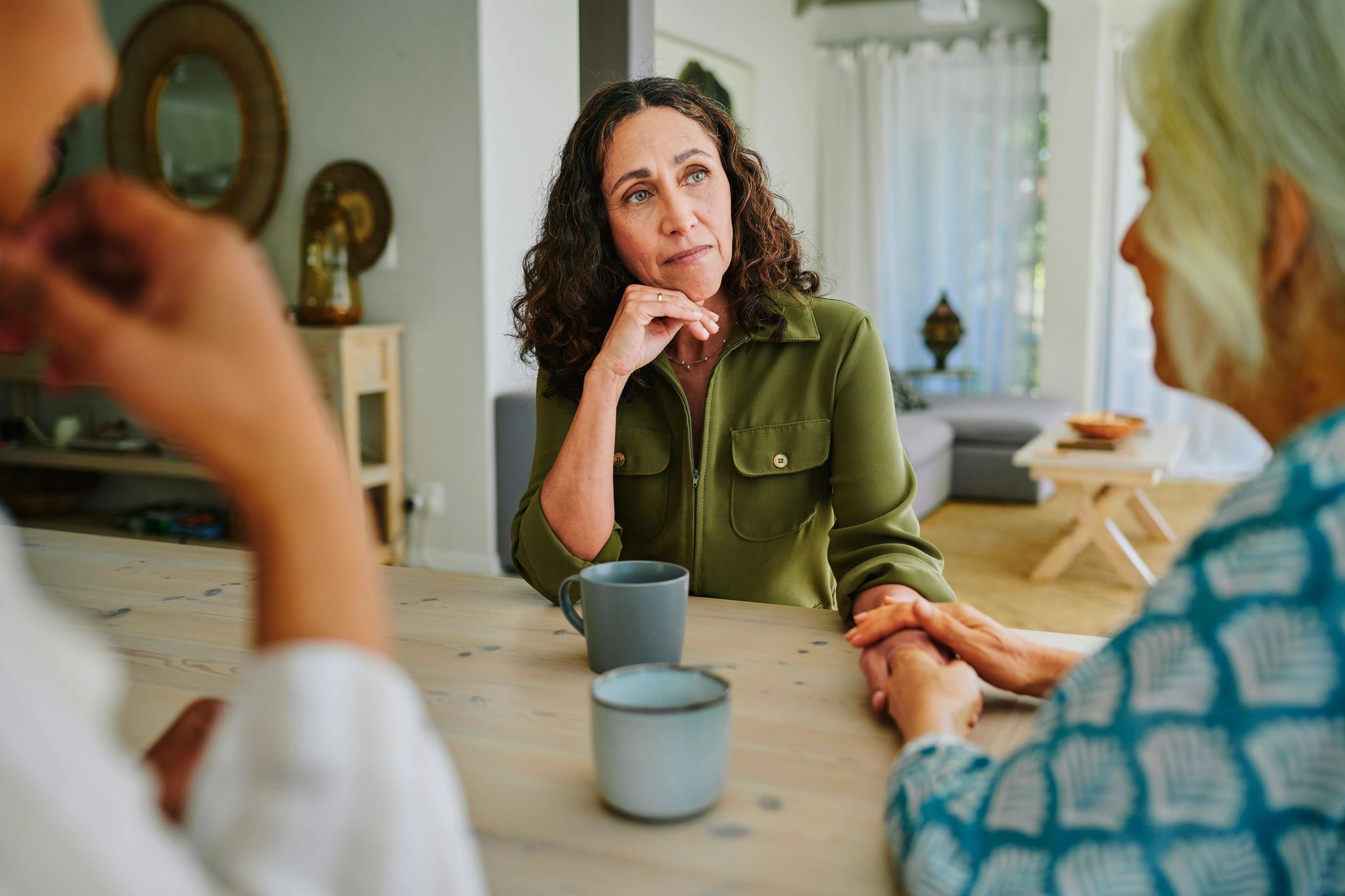 Two women talking and offering support over coffee at a table