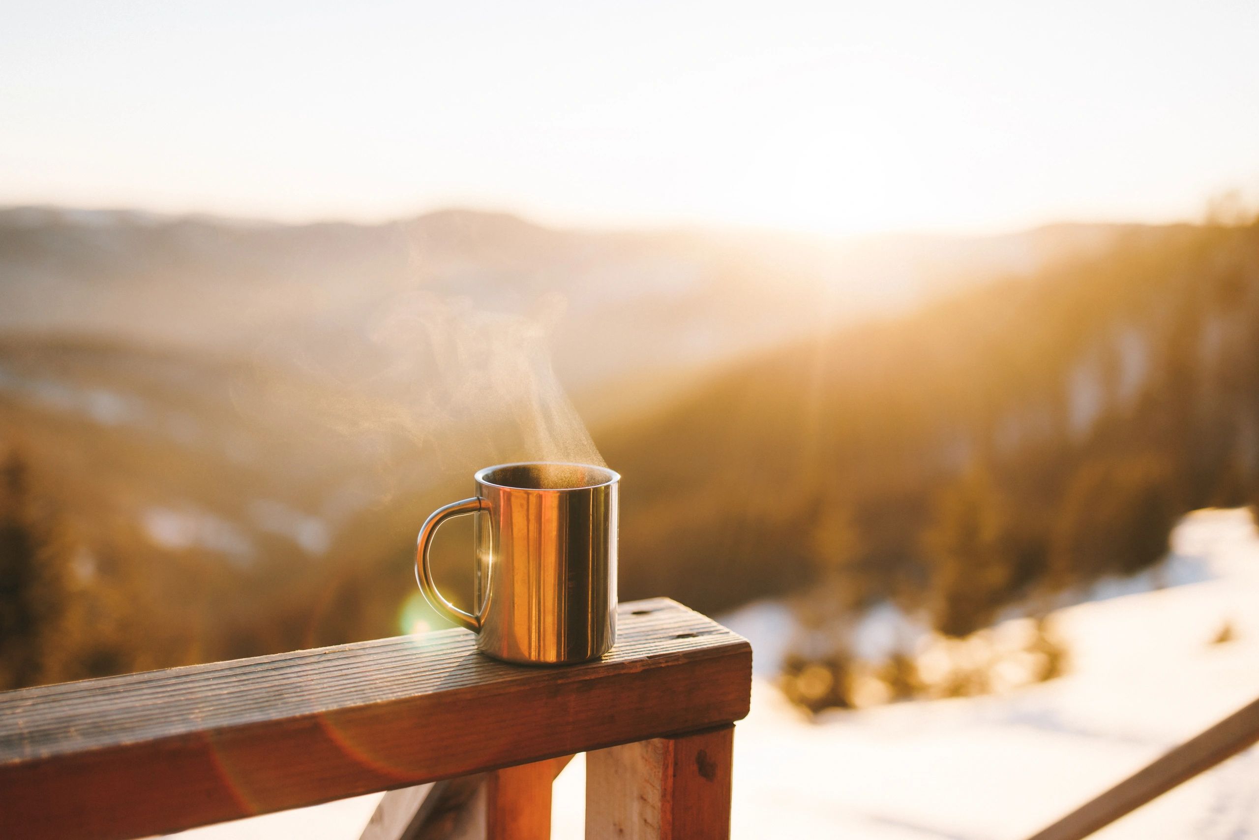 A warm coffee mug by a window at sunrise