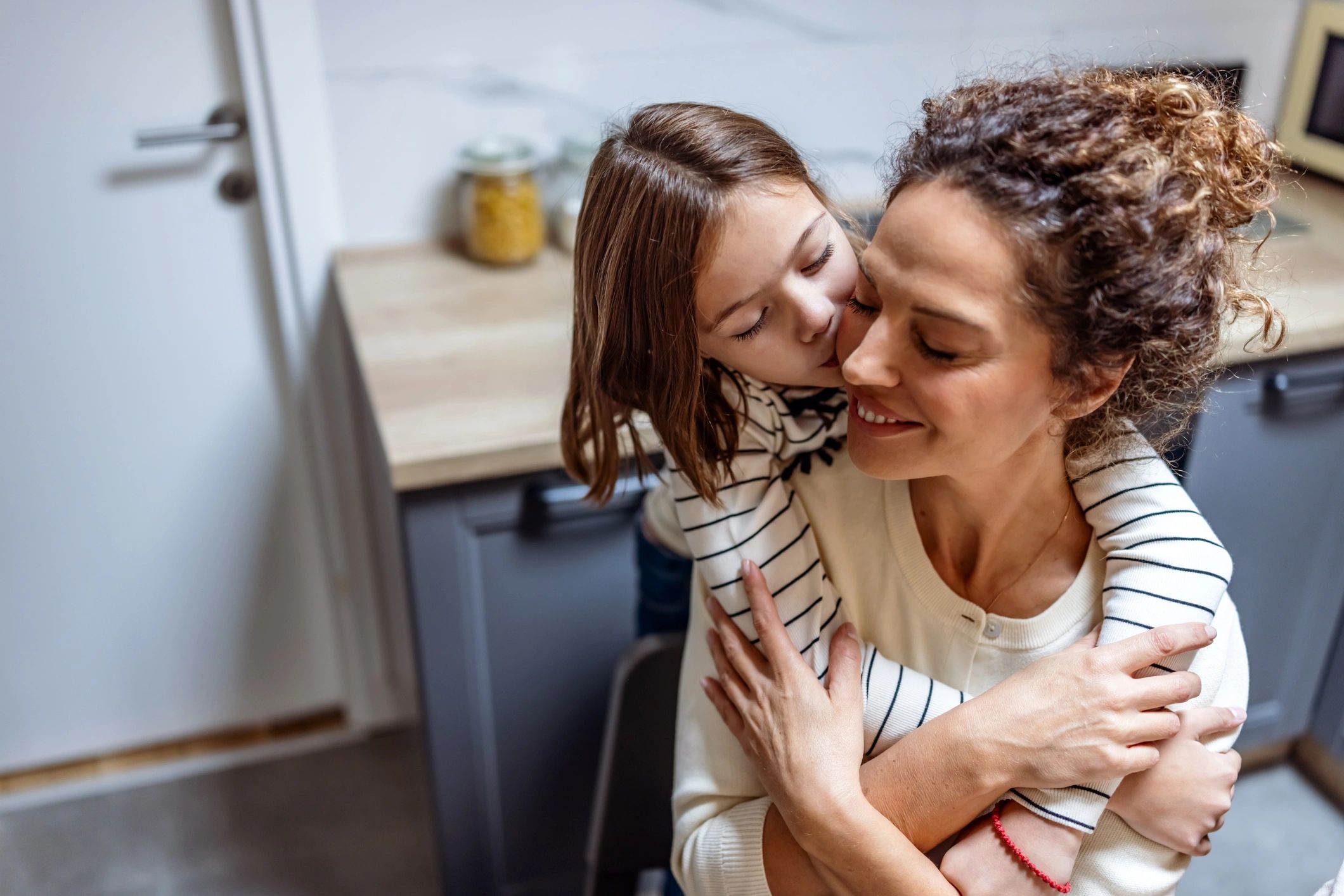 Mother and daughter hugging in a bright kitchen
